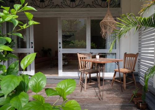 a porch with a wooden table and two chairs at Kresna By The Sea By Kresna Hospitality in Seminyak