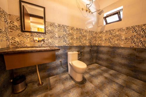 a bathroom with a toilet and a sink and a mirror at FabHotel As Residency in Dehradun