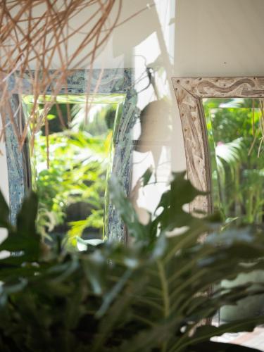 a mirror in a room with green plants at Kresna By The Sea By Kresna Hospitality in Seminyak