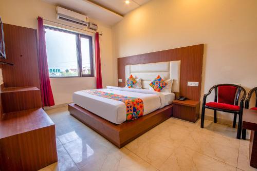 a bedroom with a large bed and a red chair at FabHotel As Residency in Dehradun