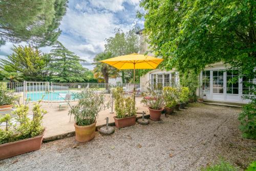 a patio with an umbrella and potted plants and a pool at Maison d'hôtes Villa Richelieu in Châtellerault