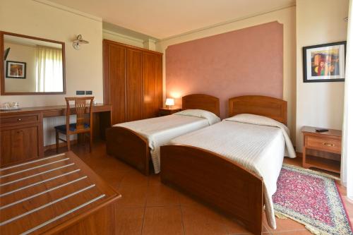 a bedroom with two beds and a desk and a mirror at Hotel Ristorante Borgovecchio in Montegrosso dʼAsti