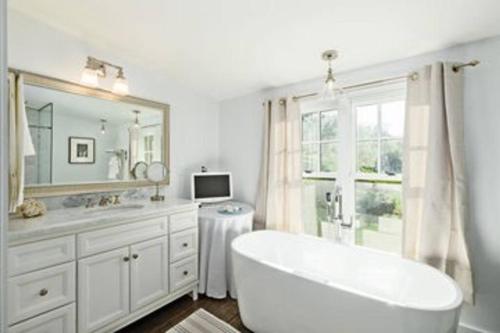 a bathroom with a tub and a sink and a mirror at Tophet Road, 3-BR with Spa Plunge Pool - PoshPadsCT in Roxbury