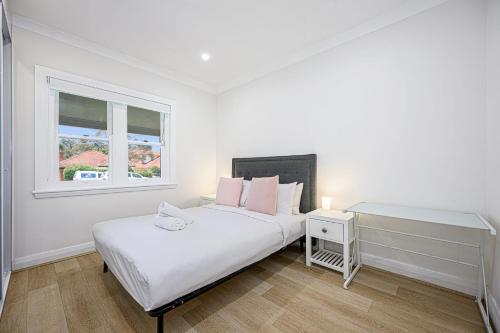 Habitación blanca con cama y ventana en Getaway For You And Your Loved Ones, en Sídney