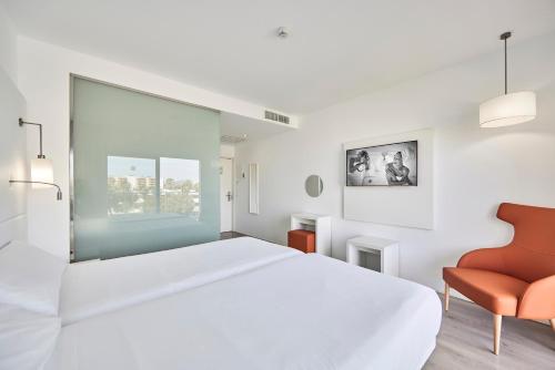 a white bedroom with a large bed and a chair at Hotel Astoria Playa Adults Only 4* Sup in Port d'Alcudia