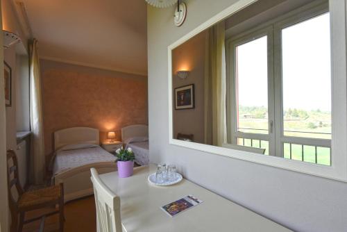 a room with a table and a mirror and a bed at Hotel Ristorante Borgovecchio in Montegrosso dʼAsti