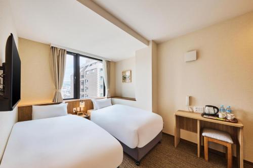 Habitación de hotel con 2 camas y escritorio en 若 京都河原町ホテル Waka Kyoto Kawaramachi Hotel, en Kioto