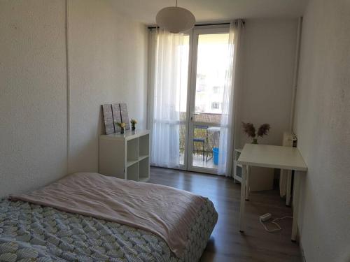 馬里尼亞訥的住宿－Appart 6 pers Marignane à 5 min -plage et aéroport，一间卧室配有一张床、一张桌子和一个窗户。