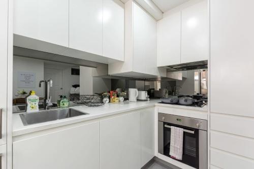 a kitchen with white cabinets and a sink at 2 BD Apt with Large Courtyard near The Star Casino in Sydney