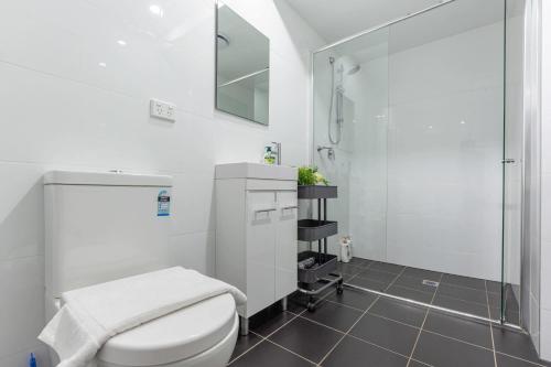 a white bathroom with a toilet and a shower at 2 BD Apt with Large Courtyard near The Star Casino in Sydney