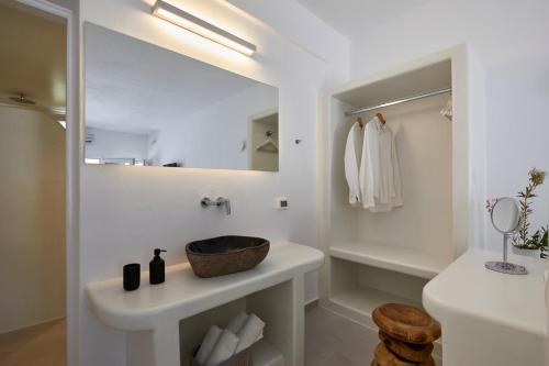 Baño blanco con lavabo y espejo en Anchor Suites, en Oia