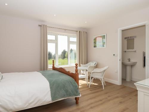 1 dormitorio con 1 cama, mesa y sillas en Hurdwick Lodge en Tavistock