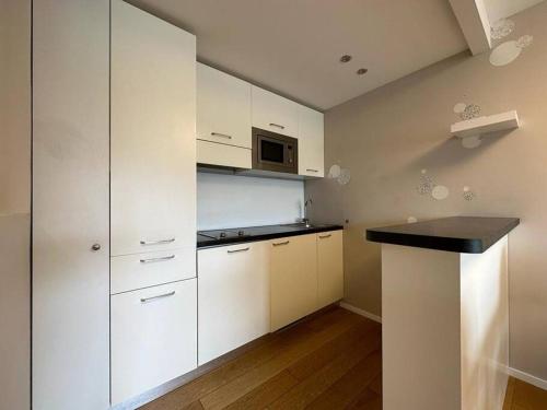 a kitchen with white cabinets and a microwave at Appartamento centrale in St. Moritz