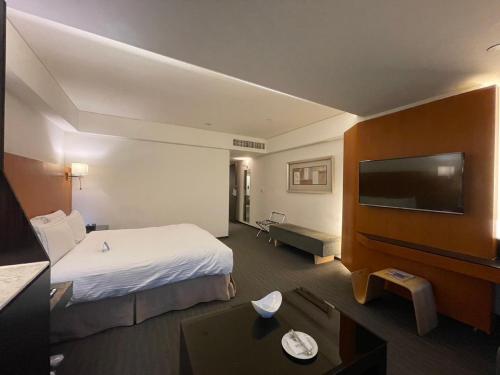 a hotel room with a bed and a flat screen tv at Tempus Hotel in Taichung