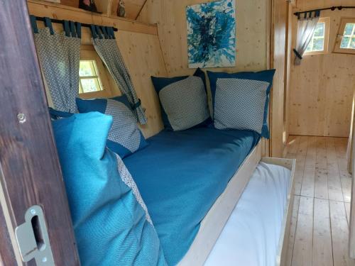 uma cama na parte de trás de uma caravana com almofadas azuis em La cabane de Merlin em Les Molières