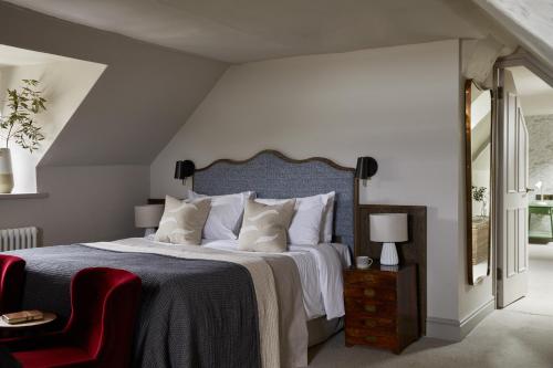 a bedroom with a large bed and a red chair at Moonfleet Manor Hotel in Weymouth
