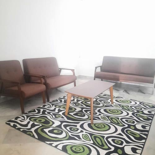 a room with two chairs and a table on a rug at Homestay Sunnah Seri Manjung Islam in Seri Manjung