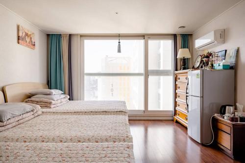 a bedroom with two beds and a refrigerator and a window at Sky Cozy House in Seoul