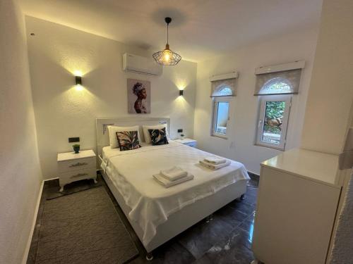 1 dormitorio con 1 cama blanca grande y 2 ventanas en Flat with Shared Pool and Garden in Kalkan Antalya, en Kalkan