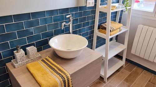 a bathroom with a sink on a wooden counter and blue tiles at Ô de Vents - à 30m de la plage in Sangatte