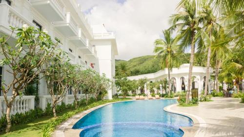 a swimming pool in the courtyard of a building with palm trees at Seaside Boutique Resort Quy Nhon in Quy Nhon
