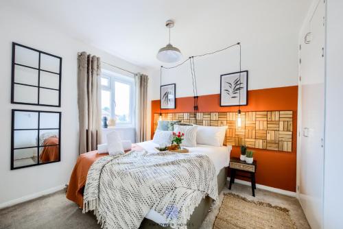 Un dormitorio con una pared de acento naranja y una cama en Coventry Beautiful House, University Hospital, M6 M69, Private Parking, Sleeps 6, by EMPOWER HOMES en Coventry