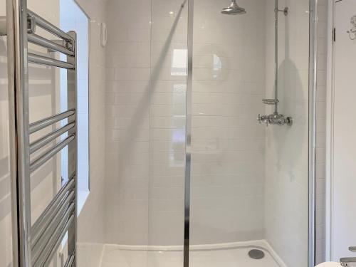 a shower with a glass door in a bathroom at Barn Cottage in Saint Mawgan