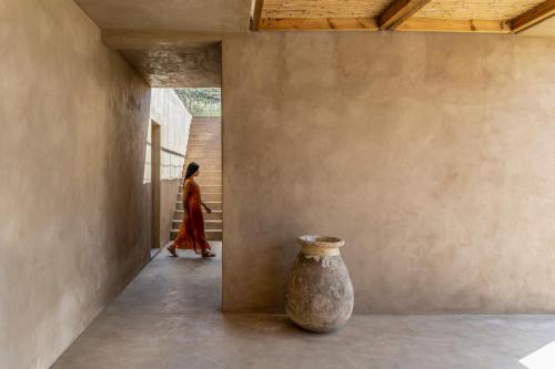 a woman walking down a hallway with a vase at Homa Serifos pool villas in Serifos Chora
