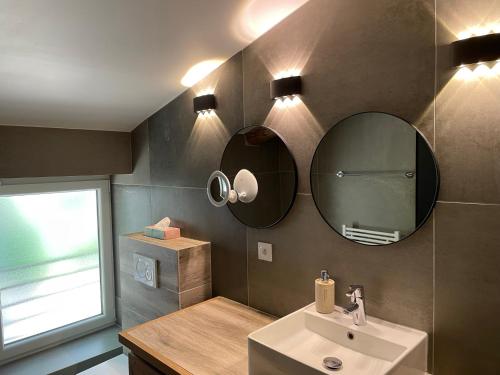 une salle de bain avec un lavabo et des miroirs au mur dans l'établissement Domaine de Calypso & Suites - Adult Only, à Auriol