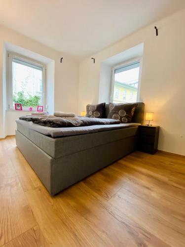 a large bed in a room with wooden floors and windows at Siriuskogel im Zentrum von Bad Ischl in Bad Ischl