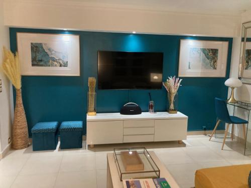 a living room with a tv and a blue wall at Appartement de standing Le Velvet Bay climatisé en bord de mer in Antibes