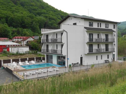 - un grand bâtiment blanc avec une piscine en face dans l'établissement Andrana, à Căciulata