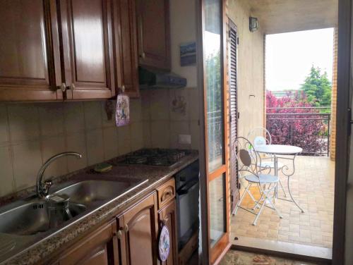 uma cozinha com um lavatório e uma varanda com uma mesa em Appartamento vacanze Assisi nel cuore em Costano