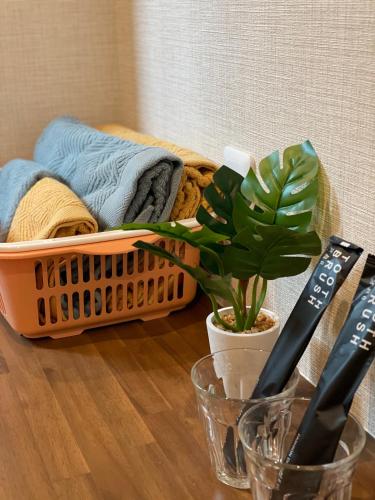 a table with a basket of towels and a plant at W&J Dream Stay in Osaka