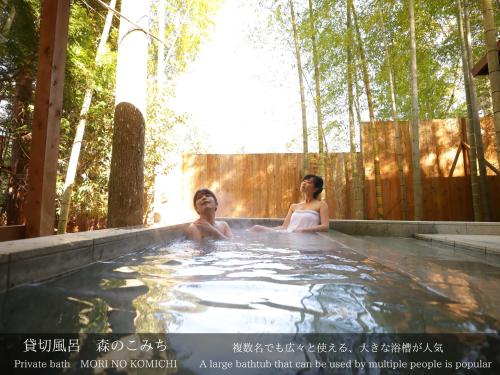 two women in a hot tub in a garden at Tatsuta Ryokan in Izu