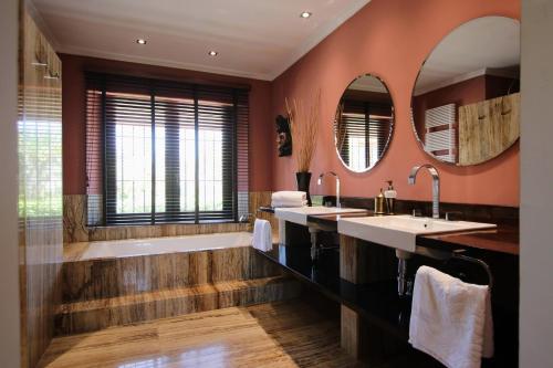 ein Badezimmer mit zwei Waschbecken, einer Badewanne und zwei Spiegeln in der Unterkunft TESS Villa Los Monteros in Alhaurín de la Torre