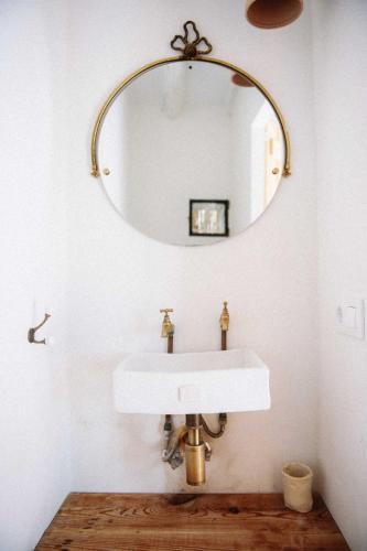 a bathroom with a white sink and a mirror at Riurau de Maria in Parcent