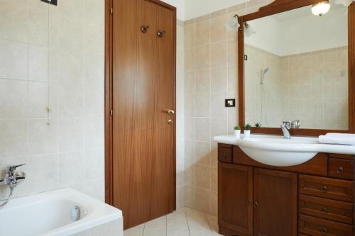y baño con lavabo, espejo y bañera. en Villa Belveder - Piscina esclusiva, Parco e Panorama, en Castelraimondo