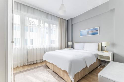 a white bedroom with a large bed and a window at Modern Stylish Cozy Flat in the Heart of Kadikoy in Istanbul