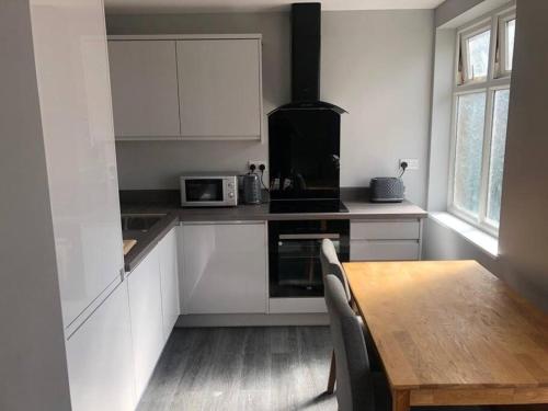 uma cozinha com armários brancos e uma mesa de madeira em New 2 bedroom first floor apartment close to beach em Southbourne