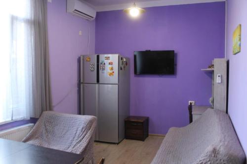 a purple room with a refrigerator and a tv at Sweet home in Tbilisi City