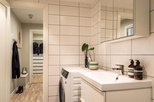 a white kitchen with a sink and a mirror at Scandinavian apartment with 2 bedrooms and terrasse - close to Storo Storsenter and all public transport in Oslo