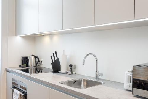 a kitchen with white cabinets and a sink at Mint@Naschmarkt Premium Apartments in Vienna