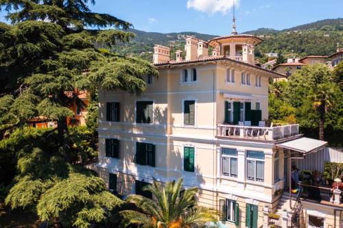 a large white house with a balcony on top of it at Apartmani Belsito in Lovran