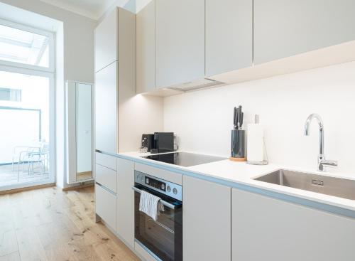 a white kitchen with a sink and a stove at Mint@Naschmarkt Premium Apartments in Vienna