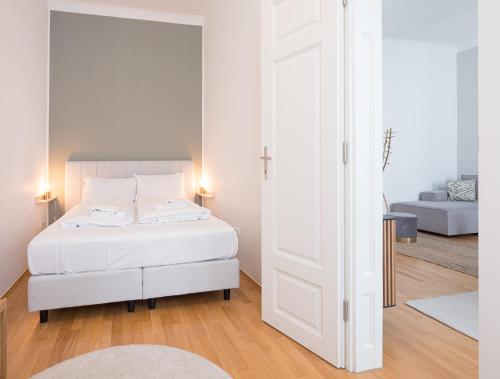 a white bedroom with a bed and a living room at Mint@Naschmarkt Premium Apartments in Vienna