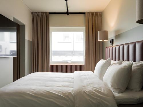 a bedroom with a white bed with a window at Elite Stadshotellet Växjö in Växjö
