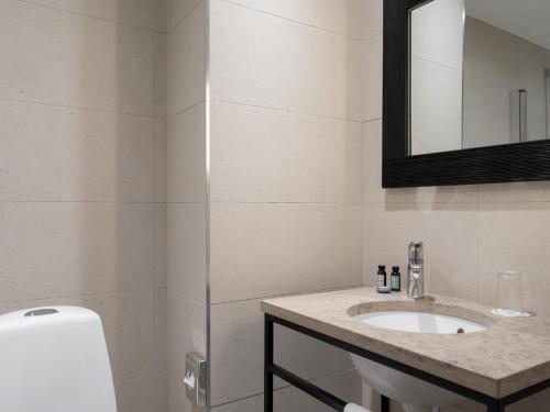 a white bathroom with a sink and a mirror at Elite Stadshotellet Växjö in Växjö