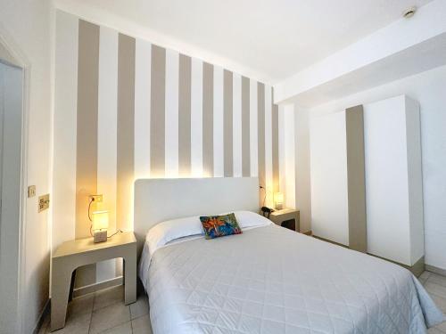 a bedroom with a bed and two tables with lamps at Aura Living Hotel in Rimini