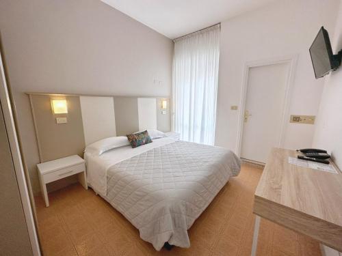 1 dormitorio con cama blanca y ventana en Aura Living Hotel, en Rímini